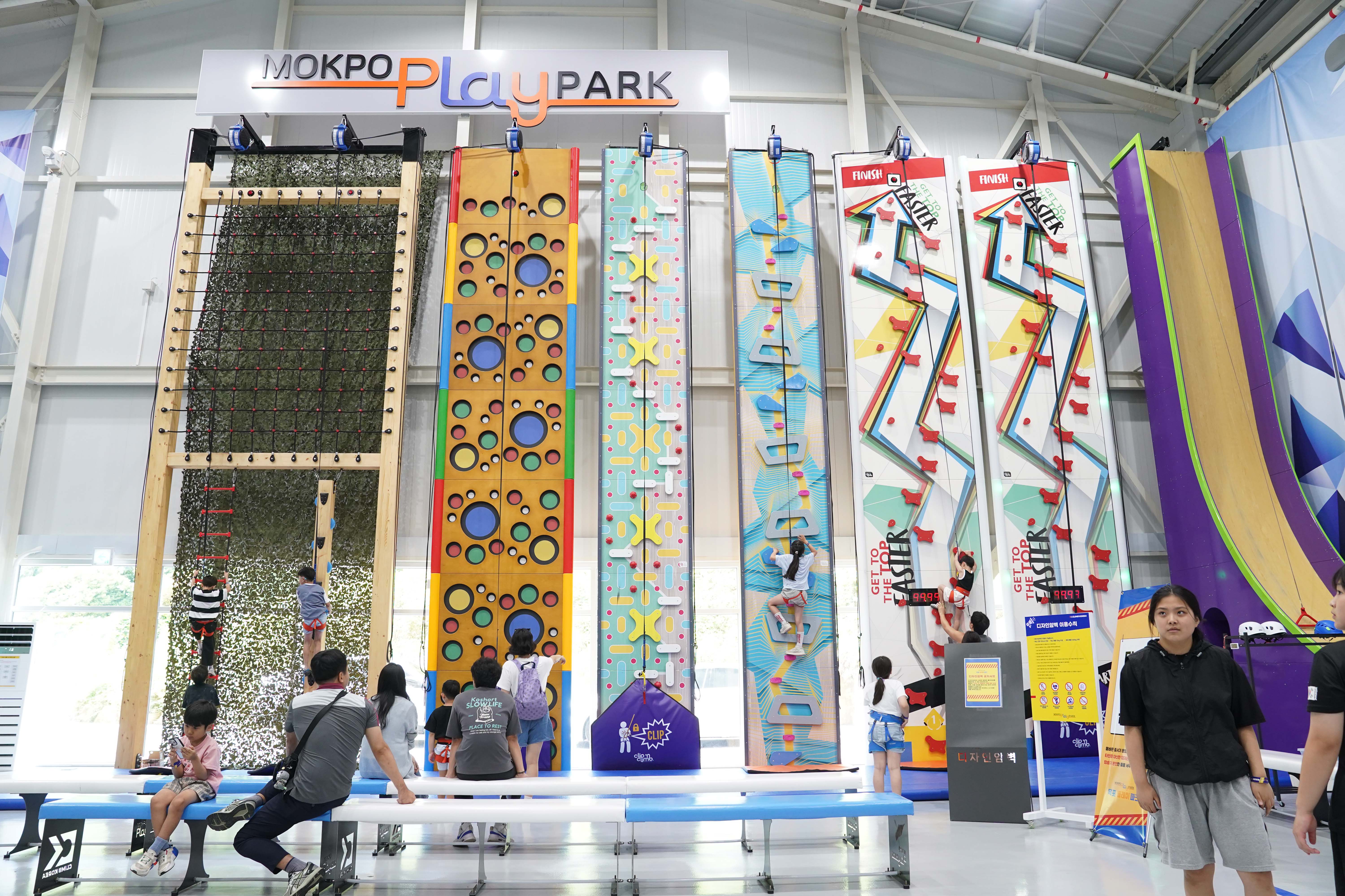 'MOKPO PLAY PARK' 로고 아래 설치된 다양한 디자인의 클라이밍 월(암벽 등반) 시설. 'GET TO THE TOP FASTER' 문구가 적힌 스피드 클라이밍 월이 포함됨.