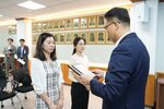 정장 차림의 관계자가 체크 원피스를 입은 여성 수상자에게 표창패를 전달하며 읽고 있는 모습이다.